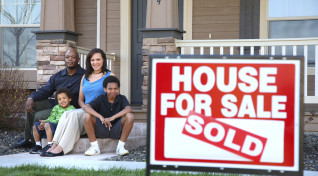 African American family sitting in front of newly purchased home